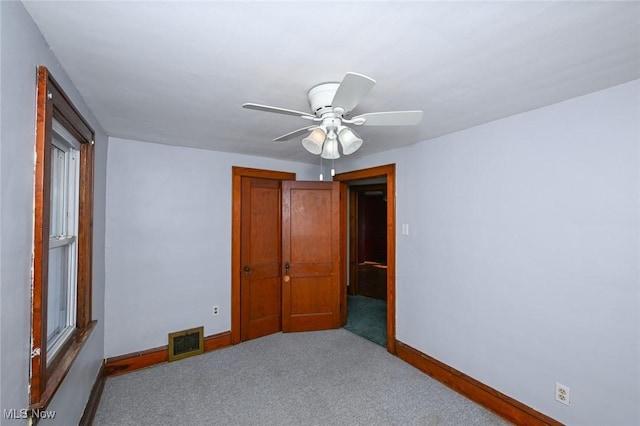 spare room featuring a ceiling fan, carpet, visible vents, and baseboards