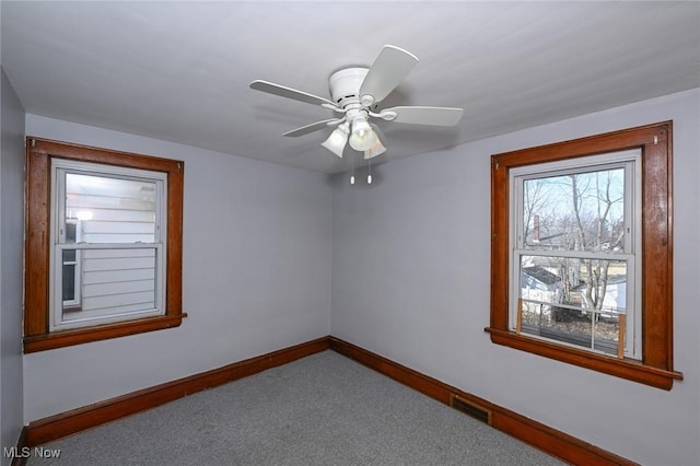 carpeted spare room featuring baseboards, visible vents, and a ceiling fan