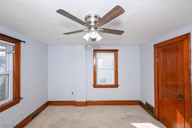 spare room featuring light carpet, visible vents, and baseboards