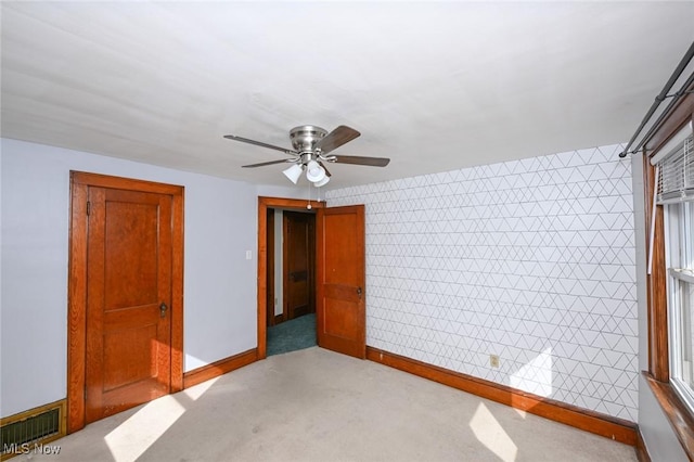 unfurnished bedroom with a ceiling fan, light colored carpet, visible vents, and baseboards