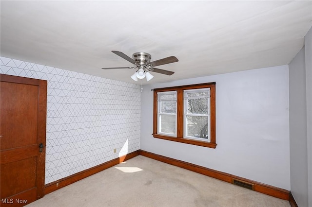 empty room featuring wallpapered walls, baseboards, visible vents, ceiling fan, and carpet flooring