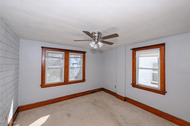 carpeted empty room featuring visible vents, baseboards, and ceiling fan