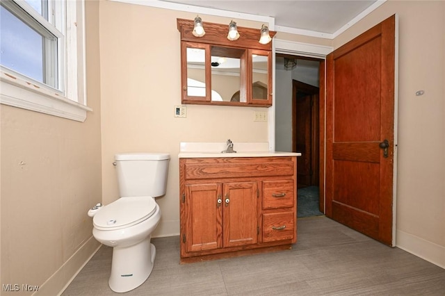 half bathroom with baseboards, vanity, and toilet