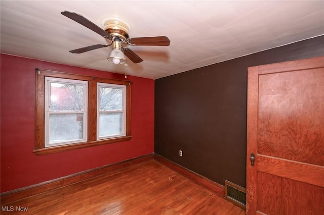 spare room featuring a ceiling fan, wood finished floors, visible vents, and baseboards