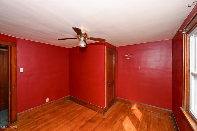 spare room featuring ceiling fan, baseboards, and wood finished floors