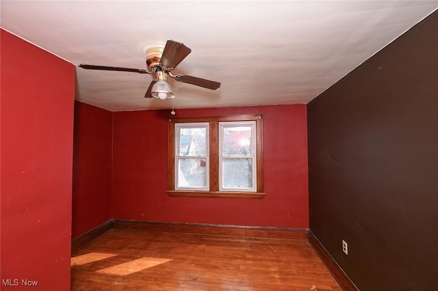 empty room featuring a ceiling fan, baseboards, and wood finished floors