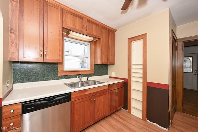 kitchen featuring a sink, light wood-style floors, light countertops, dishwasher, and tasteful backsplash