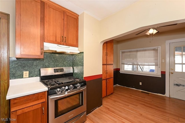 kitchen featuring light wood-style flooring, under cabinet range hood, visible vents, light countertops, and stainless steel gas range