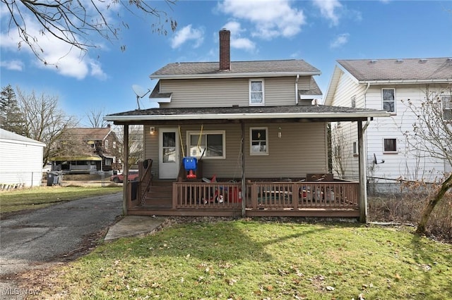 rear view of property with a chimney and a yard