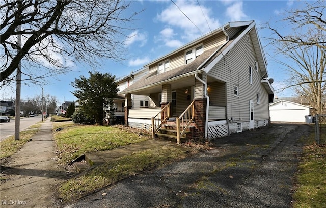 view of front of house with an outbuilding, covered porch, and a detached garage