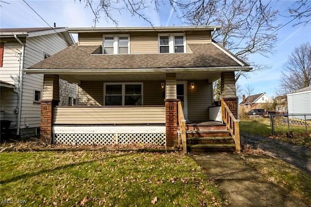 view of front of home featuring covered porch, fence, a front lawn, and roof with shingles