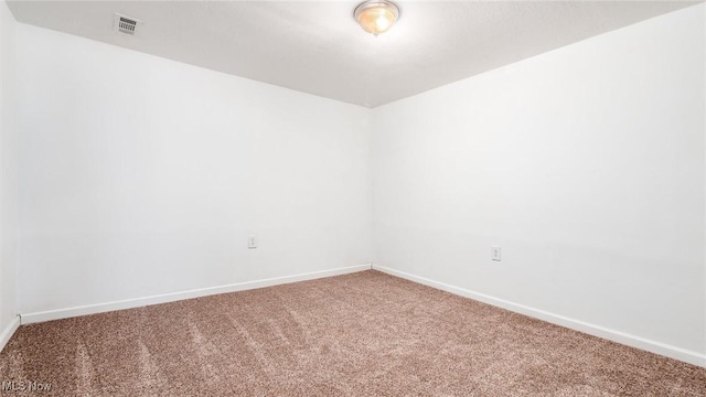 carpeted empty room featuring baseboards and visible vents