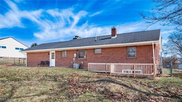 rear view of property with a chimney, fence, a lawn, and brick siding