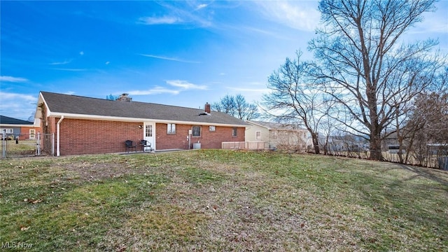 back of property featuring brick siding, fence, a yard, a chimney, and a patio area