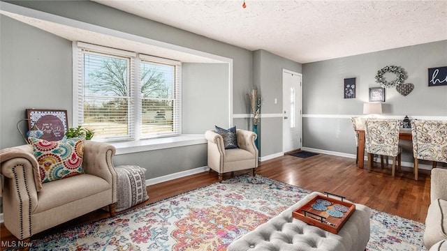 sitting room with a textured ceiling, wood finished floors, and baseboards