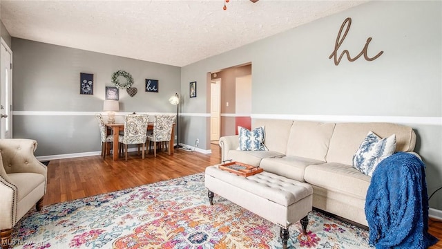 living area with a textured ceiling, wood finished floors, and baseboards