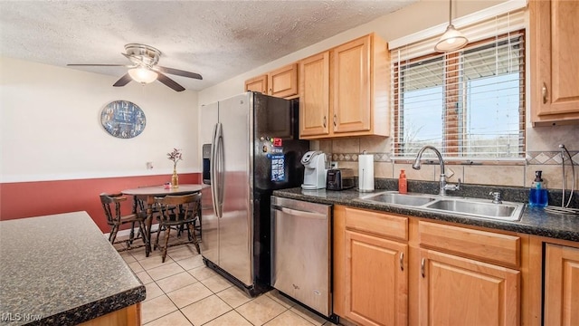 kitchen featuring ceiling fan, stainless steel appliances, a sink, backsplash, and dark countertops