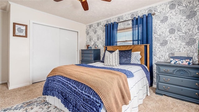 bedroom featuring carpet, crown molding, a closet, ceiling fan, and a textured ceiling