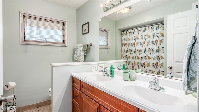 full bathroom with double vanity, a sink, toilet, and tile patterned floors