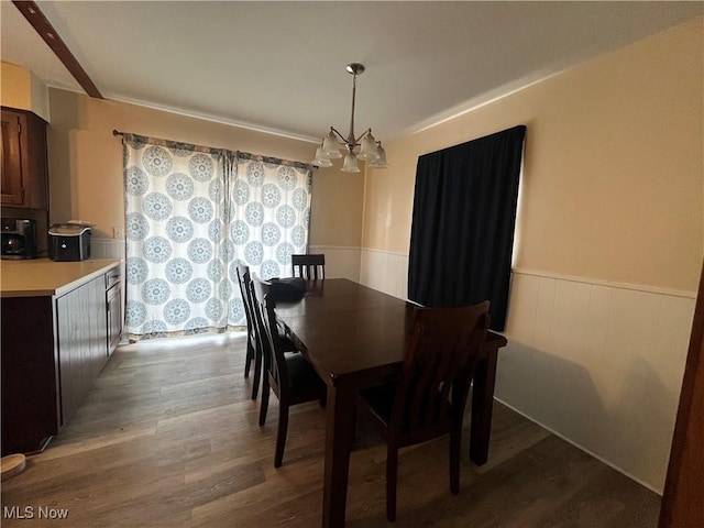 dining space featuring wainscoting, wood finished floors, and an inviting chandelier