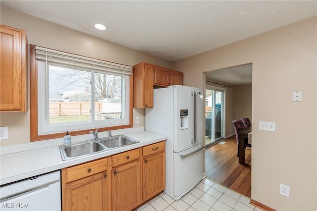 kitchen with light tile patterned floors, recessed lighting, white appliances, a sink, and light countertops