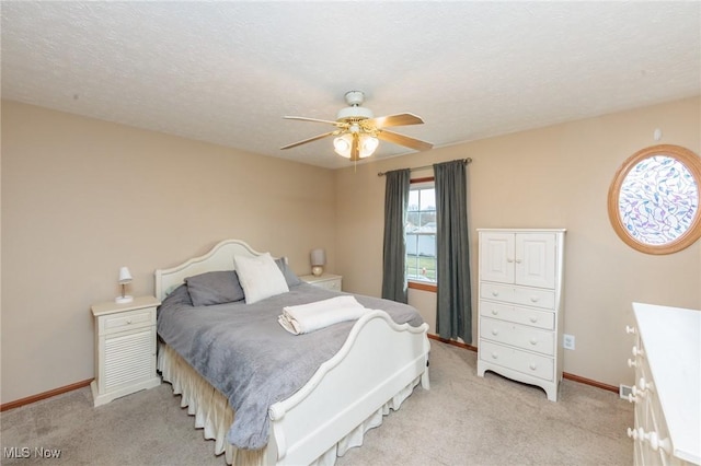 bedroom featuring light carpet, baseboards, and a textured ceiling