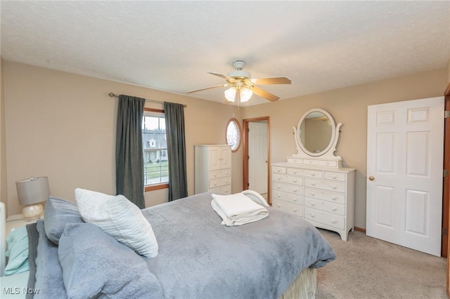 bedroom featuring a ceiling fan, light carpet, and a textured ceiling