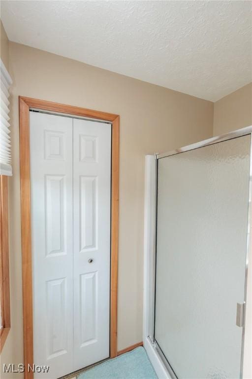 full bathroom featuring a shower stall and a textured ceiling