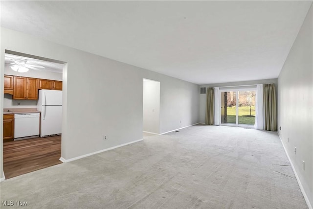 unfurnished living room with light carpet, ceiling fan, and baseboards