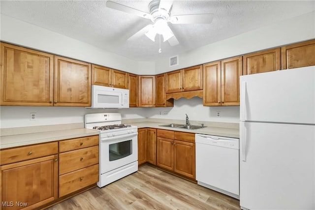 kitchen featuring white appliances, light wood-type flooring, a sink, and brown cabinets