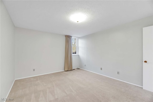 unfurnished room with baseboards, a textured ceiling, and light colored carpet