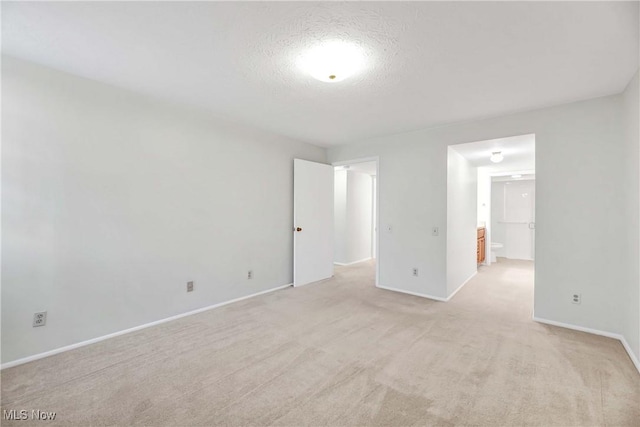 interior space with light colored carpet, a textured ceiling, and baseboards