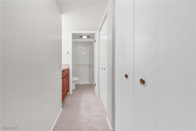 hallway with light colored carpet and baseboards