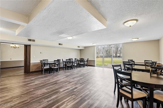 dining area featuring a textured ceiling, wood finished floors, and visible vents