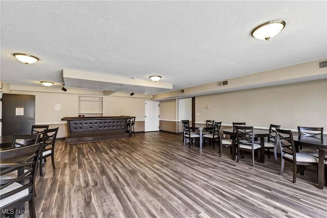 dining space with a textured ceiling, visible vents, and wood finished floors