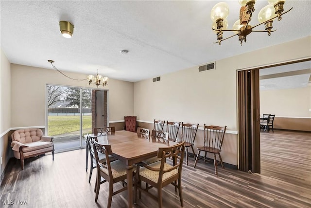 dining area featuring a chandelier, a textured ceiling, wood finished floors, and visible vents