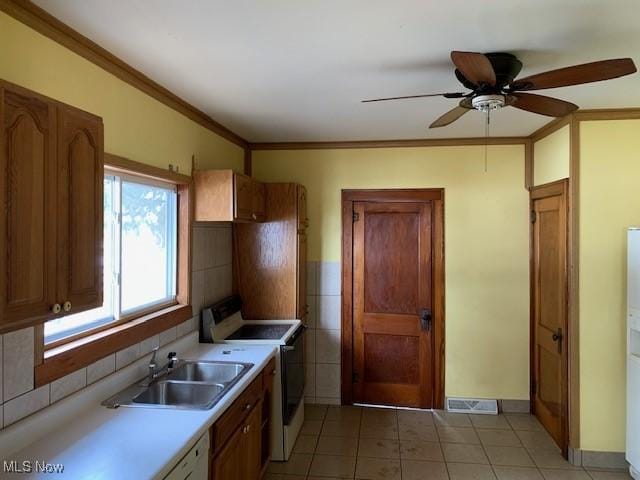 kitchen featuring white appliances, a sink, light countertops, brown cabinets, and crown molding