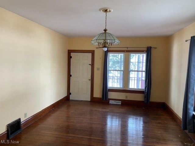 empty room with baseboards, visible vents, and wood finished floors