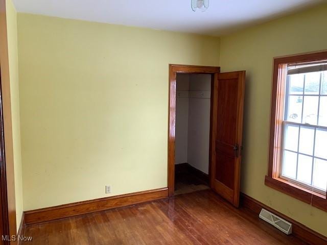 unfurnished room featuring wood finished floors, visible vents, and baseboards