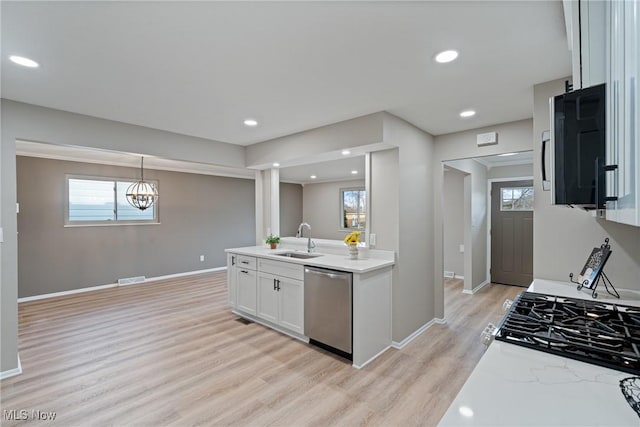 kitchen featuring light wood-type flooring, appliances with stainless steel finishes, white cabinets, and a sink