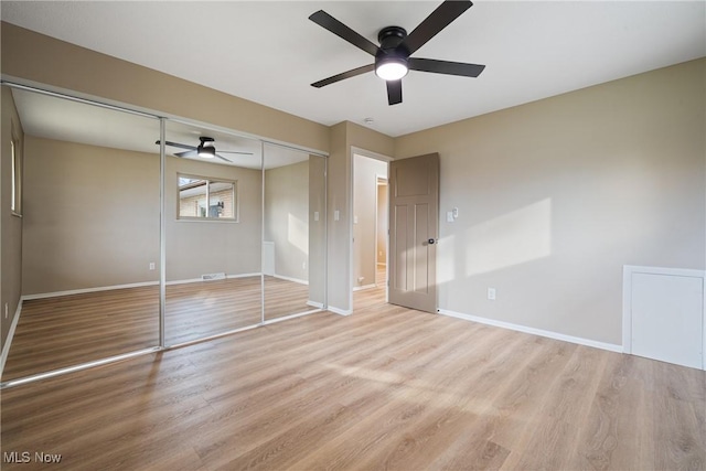 unfurnished bedroom featuring a closet, wood finished floors, a ceiling fan, and baseboards