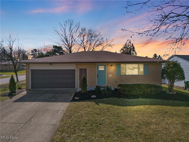 ranch-style home with a garage, concrete driveway, brick siding, and a lawn