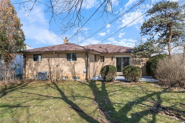 back of property with central AC, brick siding, a lawn, and a chimney