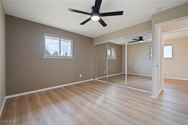 unfurnished bedroom with light wood-style floors, multiple windows, and baseboards