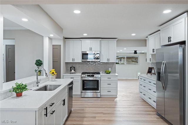 kitchen with light wood-type flooring, white cabinets, stainless steel appliances, and a sink