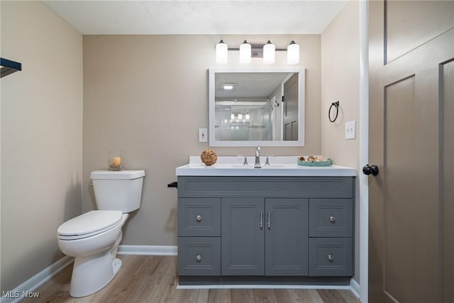 bathroom featuring baseboards, vanity, toilet, and wood finished floors