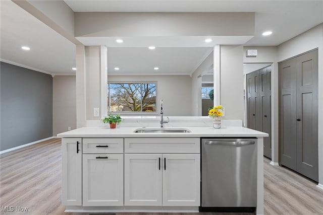 kitchen with a sink, light wood finished floors, ornamental molding, and stainless steel dishwasher