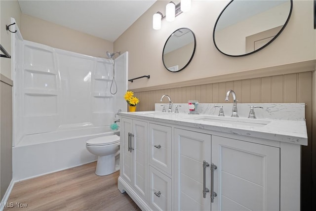 bathroom with toilet, shower / bathtub combination, a sink, and wood finished floors