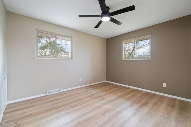 empty room featuring a healthy amount of sunlight, light wood-style flooring, and visible vents