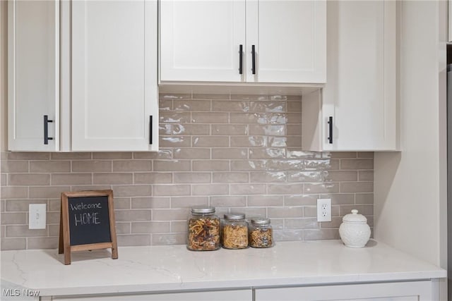 details featuring light stone countertops, white cabinetry, and backsplash